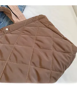 Close-up of brown quilted nylon tote bag featuring diamond stitching and silver metal buckle