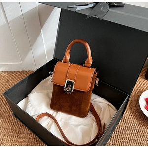 Close-up of retro crossbody bag in brown matte suede and leather inside a gift box
