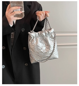 Detail of silver quilted bucket bag with metallic finish and metal chain strap