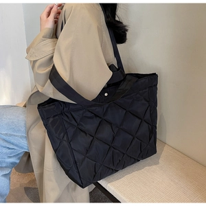 Lifestyle view of a large black quilted nylon tote bag with silver magnetic closure