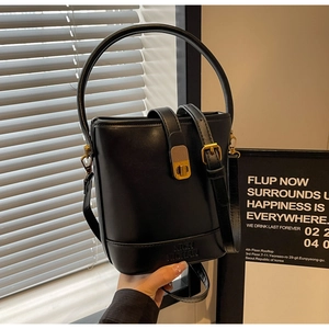 Détail du sac seau en cuir noir avec serrure dorée et poignée ronde rigide