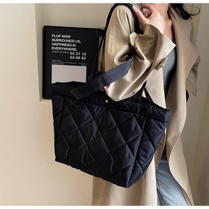 Close-up of black quilted nylon tote bag with metal snap button and diamond patterns