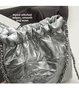 Close-up of silver quilted bucket bag featuring drawstring closure and chain strap detail