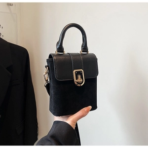 Detail of black matte suede crossbody bag with elegant gold twist lock and smooth handle