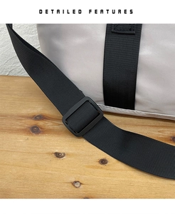 Detail of adjustable black nylon shoulder strap with matte plastic buckle on grey tote bag