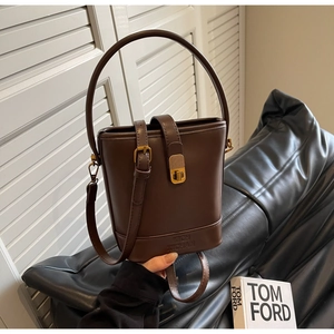 Détail d'un sac seau en cuir synthétique marron foncé avec fermoir rotatif doré