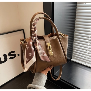 Detail of dark brown leather bucket bag featuring gold twist lock and heart pattern scarf