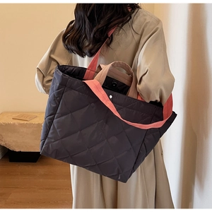 Detail of diamond quilted nylon tote bag with contrasting orange and beige straps