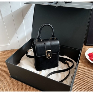 Detail of minimalist black leather handbag with gold clasp in a luxury gift box