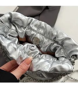 Detailed macro view of quilted silver metallic bucket bag with magnetic snap and chain strap