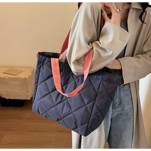 Close-up of quilted nylon tote bag with pink contrast handles and diamond stitching