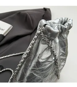 Close-up of metallic silver bucket bag with quilted patterns and silver chain strap detail