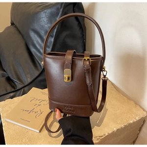 Vue détaillée du sac seau en cuir marron foncé avec boucle et bandoulière dorées rétro