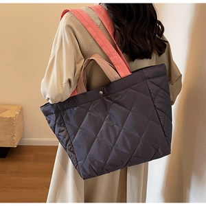 Detail of grey quilted tote bag with pink straps showing metallic snap closure and texture