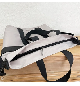 Close-up of a large grey nylon tote bag showing the zipper and wide black shoulder strap