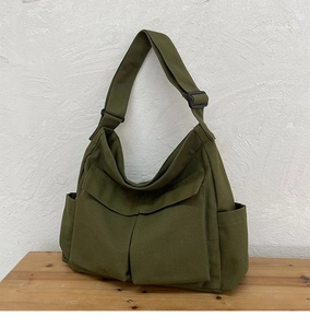 Dettaglio borsa a tracolla vintage in tela verde militare con tasche anteriori e spallina