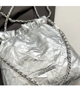 Close-up of silver quilted bucket bag with chain strap and metallic logo detail