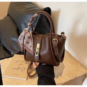 Detail of vintage brown bucket bag with lychee texture and heart print silk scarf