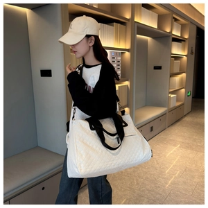 Detalle de bolsa de viaje acolchada blanca con asas negras y correa para mujer