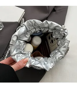 Macro view of silver pleated bucket bag interior showing large capacity and chain strap