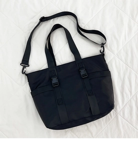 Detail of black nylon tote bag with functional buckles and adjustable shoulder strap