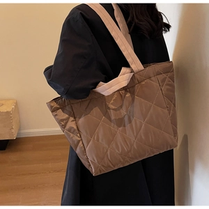 Detail of a brown quilted nylon tote bag featuring durable stitching and silk-like finish