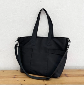 Detail of durable black nylon tote bag with reinforced handles and removable shoulder strap