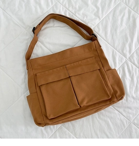 Dettaglio della borsa tote in tela marrone con tasche frontali e tracolla regolabile