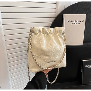 Detail of cream quilted bucket bag with silver chain strap and drawstring closure
