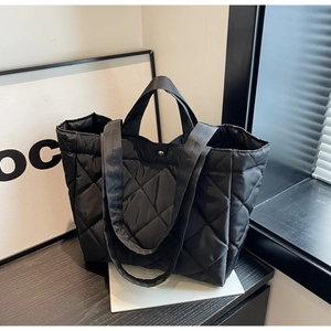 Macro shot of minimalist black quilted nylon tote bag with diamond lattice pattern