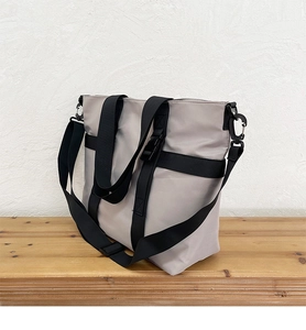 Close-up of light gray waterproof tote bag with black webbing straps and buckle detail