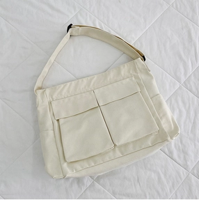 Dettaglio della borsa a tracolla in tela crema con grandi tasche e cinghia regolabile
