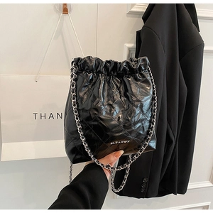 Close-up of black quilted bucket bag with silver chain strap and drawstring closure
