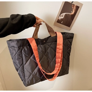 Detail view of a large quilted nylon tote bag with orange straps and snap closure