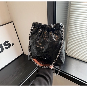 Detail of black quilted leather bucket bag with silver chain strap and drawstring closure