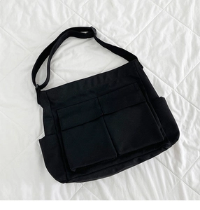 Dettaglio borsa tote in tela nera con tasche a patta e tracolla regolabile