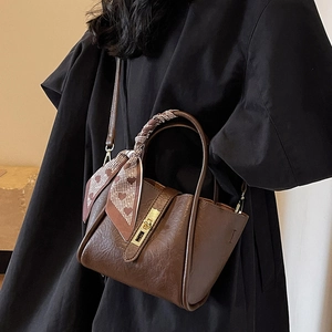 Brown leather bucket bag with top handle, crossbody strap, and chic heart pattern scarf