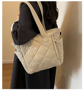 Detailed side view of a beige quilted nylon tote bag showing the textured diamond pattern