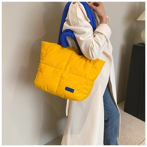 Sac cabas matelassé jaune avec anses bleues et détail de l'étiquette mode