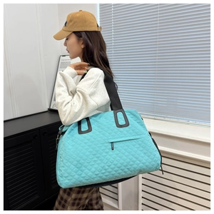 Bolso de viaje acolchado azul llevado por una modelo en un interior moderno y minimalista
