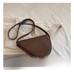 Dettagli della texture in pelle opaca marrone scuro e della tracolla regolabile della borsa