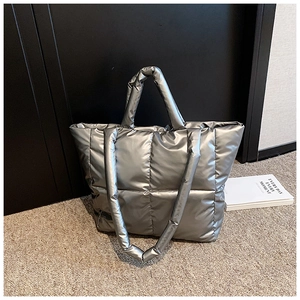 Détail du sac fourre-tout matelassé argenté avec poignées rembourrées sur tapis gris