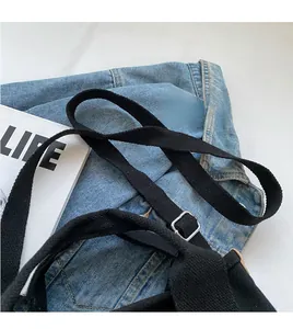 Detail of black canvas bag strap featuring an adjustable silver metal buckle and durable webbing