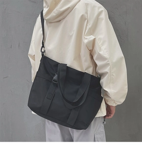 Detail of black water-resistant nylon tote bag with wide strap and buckle closure