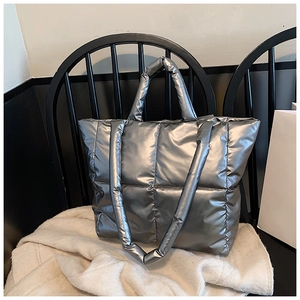 Détail de la texture matelassée argentée et de la poignée rembourrée du grand sac fourre-tout