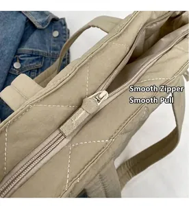 Detail of smooth metal zipper and quilted texture on beige nylon tote bag