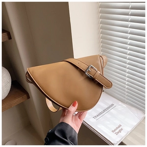 Dettaglio della borsa a sella in pelle sintetica kaki con fibbia decorativa in argento sul manico