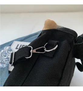 Detail of silver metal hardware and brown leather trim on black canvas bag