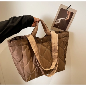 Detail of dark brown quilted nylon tote bag with dual straps and silver snap button