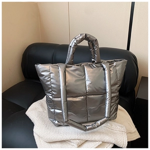 Gros plan d'un sac cabas argenté matelassé avec poignées rembourrées sur maille blanche